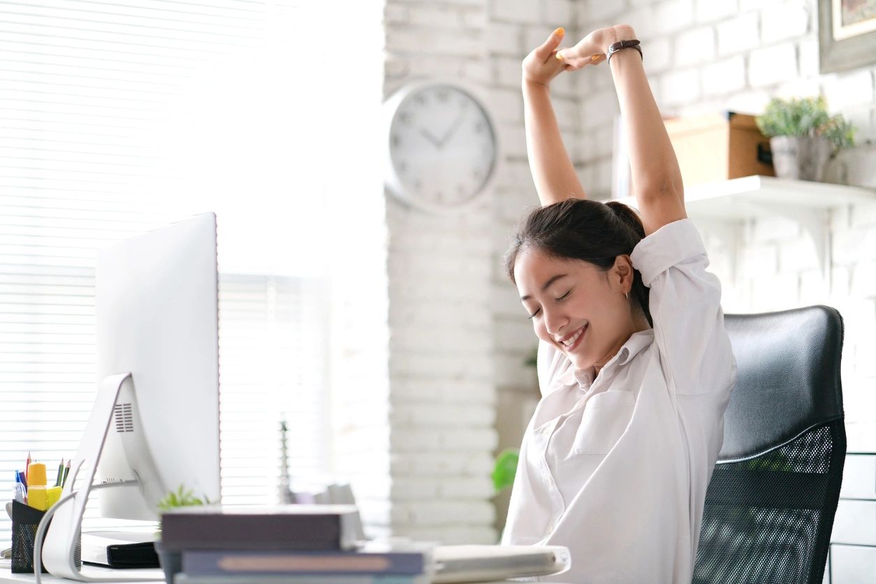 woman stretching at her desk during the workday